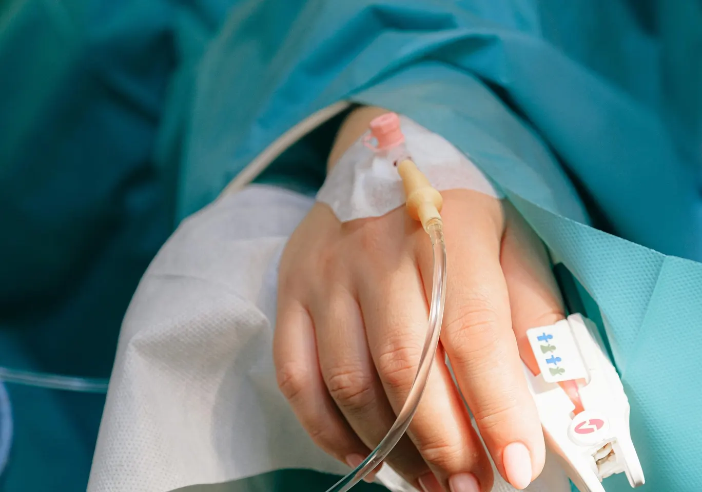 Odtrucie alkoholowe Białystok: dłoń z wenflonem i pulsoksymetrem pod nadzorem