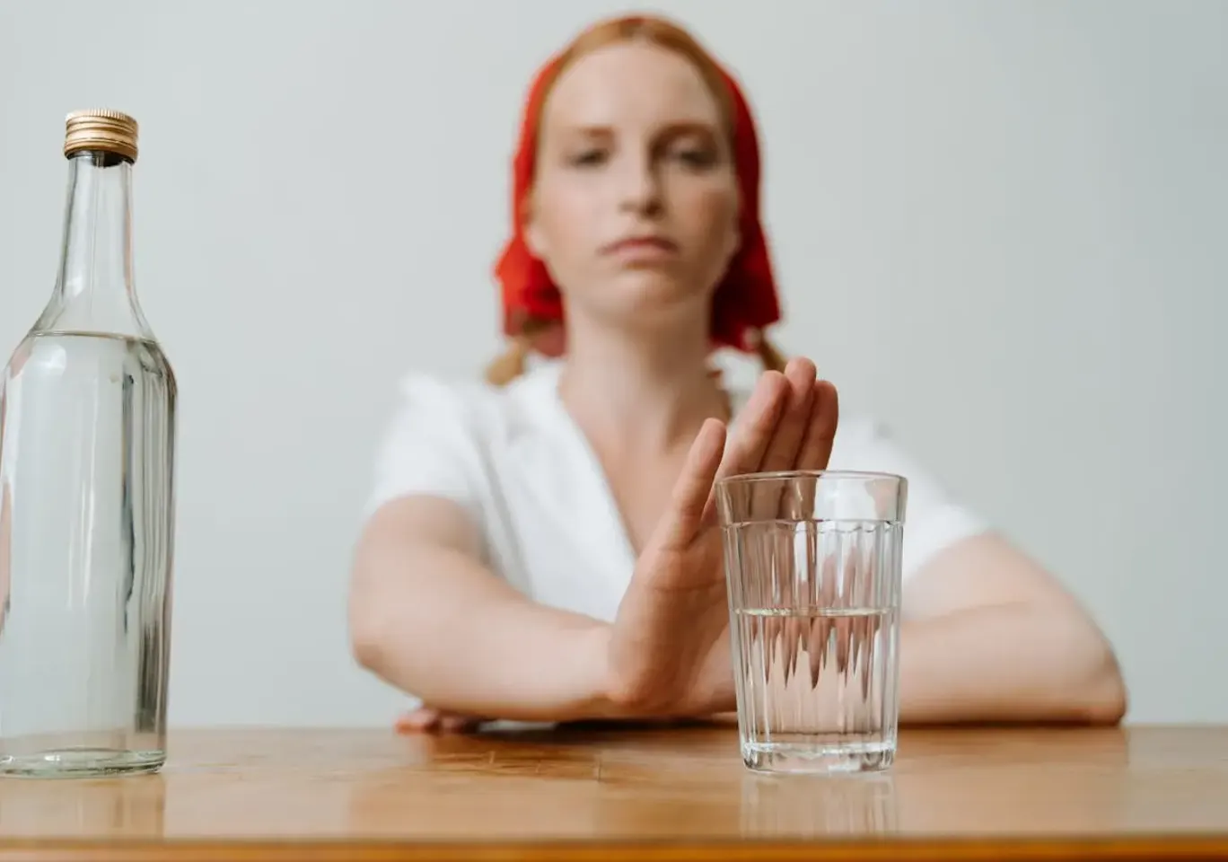 Leczenie alkoholizmu Białystok: kobieta odsuwa butelkę i sięga po wodę