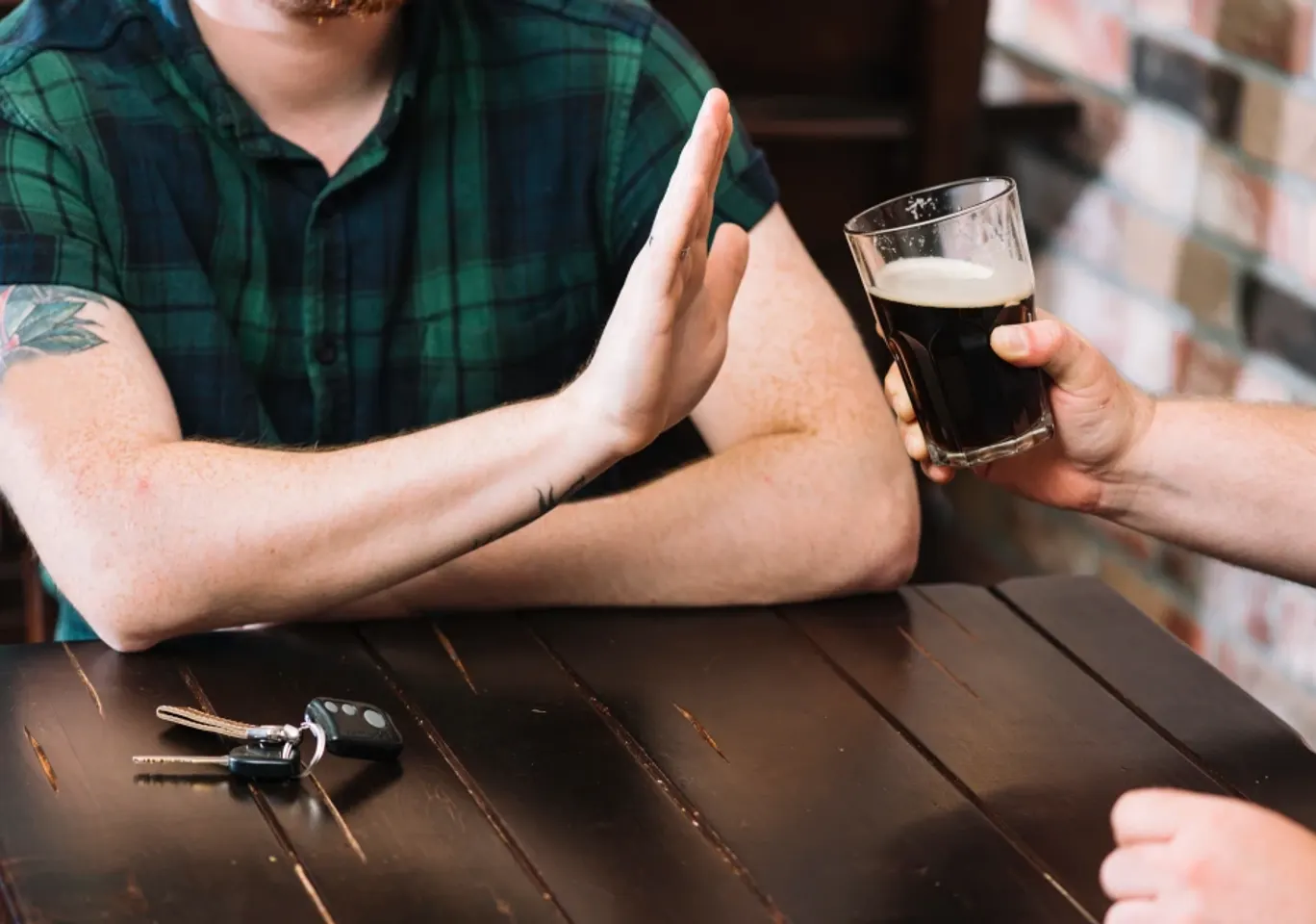Leczenie alkoholizmu Białystok: dłoń odmawiająca kufla piwa przy stole